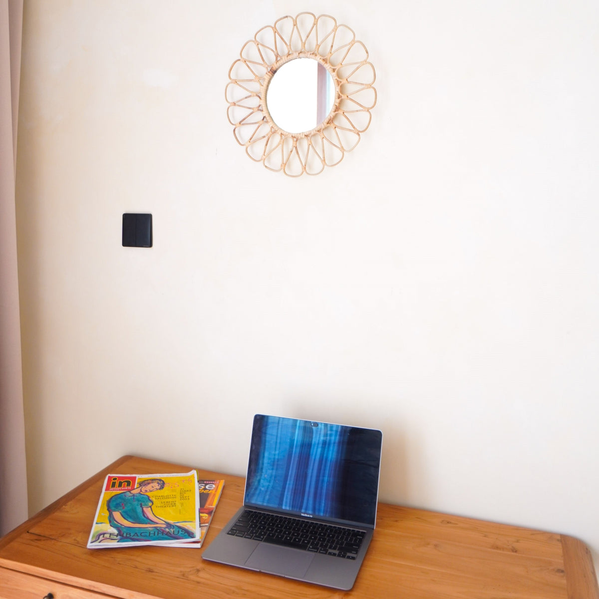Soeji Rattanspiegel DANAU an cremefarbener Wand über einem Schreibtisch mit Laptop